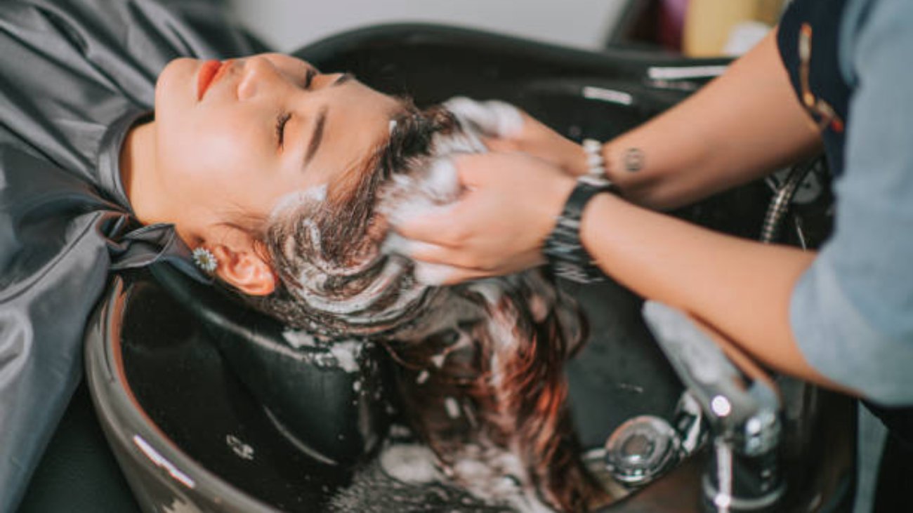 Directly above Asian chinese female lying down for hair wash at hair salon with eyes closed