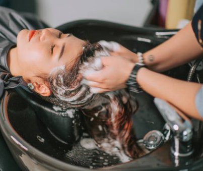 Directly above Asian chinese female lying down for hair wash at hair salon with eyes closed