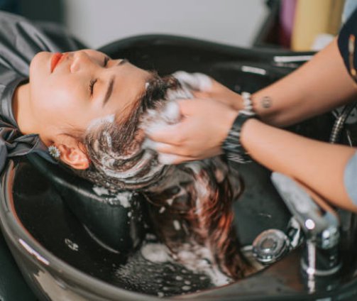 Directly above Asian chinese female lying down for hair wash at hair salon with eyes closed