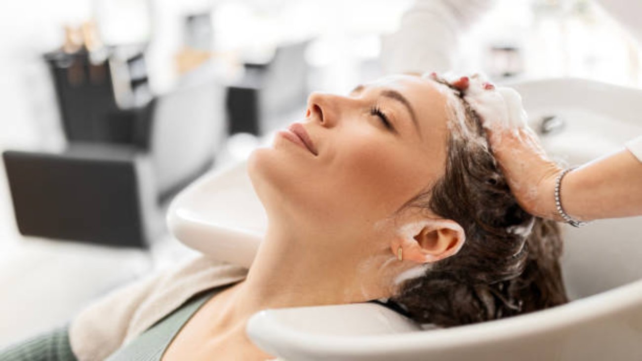 Hairdresser washing young woman's hair in salon