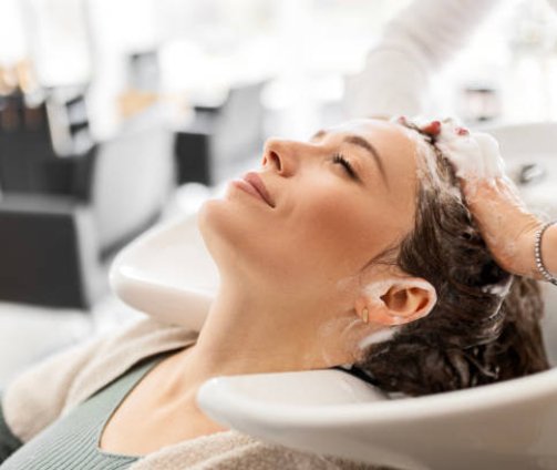 Hairdresser washing young woman's hair in salon